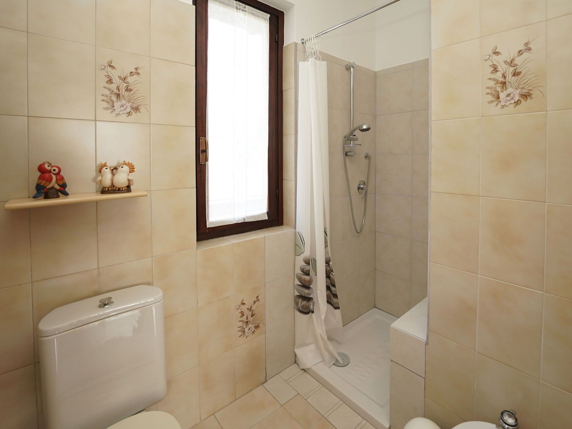 Une salle de bain équipée de toilettes, d’une douche et d’une fenêtre avec un rideau.