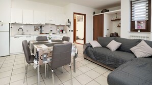 Een knus woongedeelte met een kitchenette, een eethoek en een bank.
