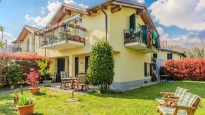 A two-story house with a balcony, a small garden, and outdoor furniture. - Cosy apartment for 4 people with WIFI, TV, terrace and pets allowed (Gravedona)
