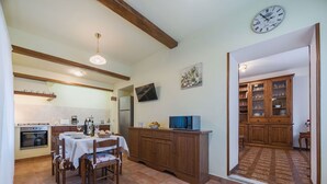 Una cocina con una mesa de comedor, sillas, un refrigerador y un microondas.