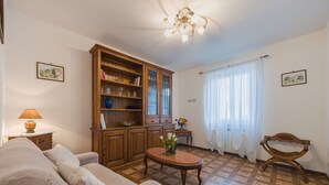 Una sala de estar con un sofá, un mueble de madera, una mesa con flores y una araña.