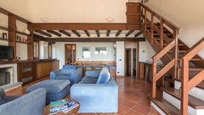 Amplia sala de estar con chimenea, sofás y una escalera de madera.