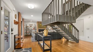 Un interior moderno con una escalera, piso de madera y una sala de estar con sofá y objetos decorativos.