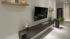 Moderni olohuone, jossa on litteänäyttöinen televisio, tumma konsolipöytä ja koriste-esineitä.