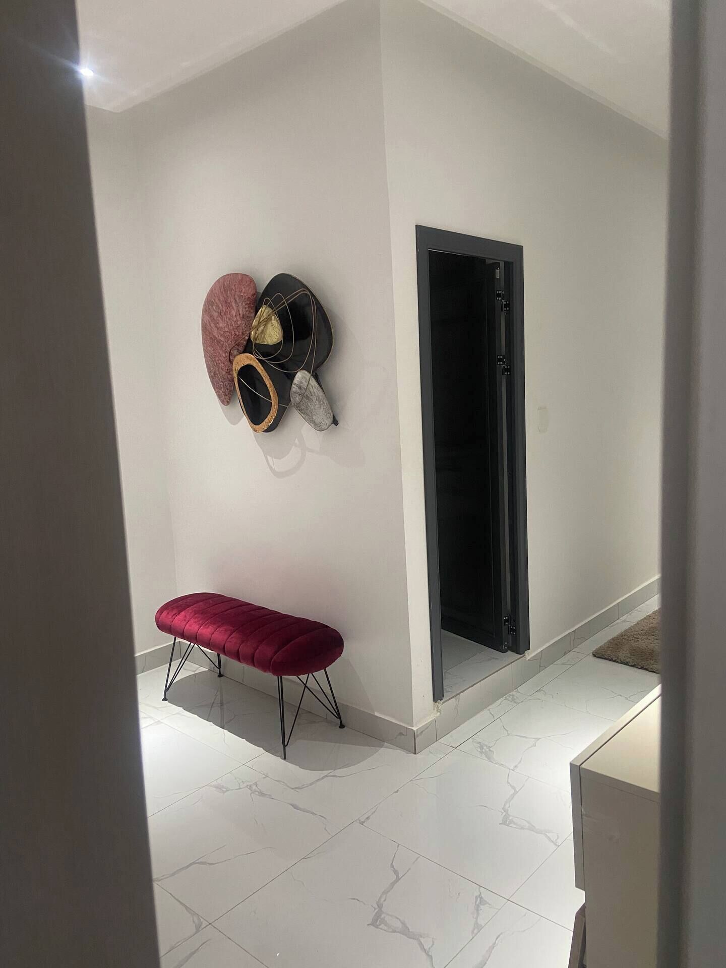 Une pièce moderne avec un banc, un casque fixé au mur et une porte.