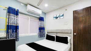 Un dormitorio con cama, cortinas, ventana, aire acondicionado, un cuadro en la pared y una puerta.