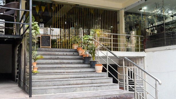 Una escalera con barandas de metal, plantas en macetas y un cartel.