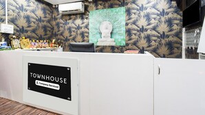 Un mostrador de recepción con un cartel que dice 'TOWNHOUSE Company Serviced', una estatua y un papel tapiz estampado.