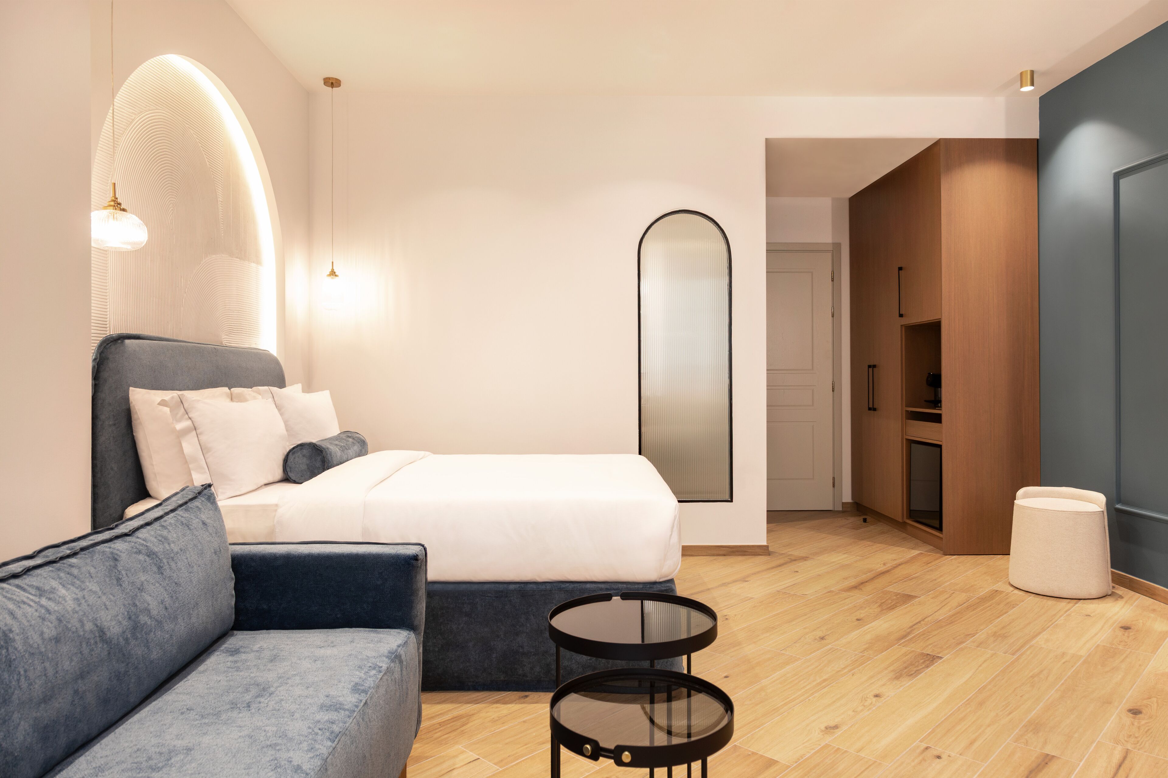 A modern bedroom with a bed, a sofa, a round table, and a mirror.