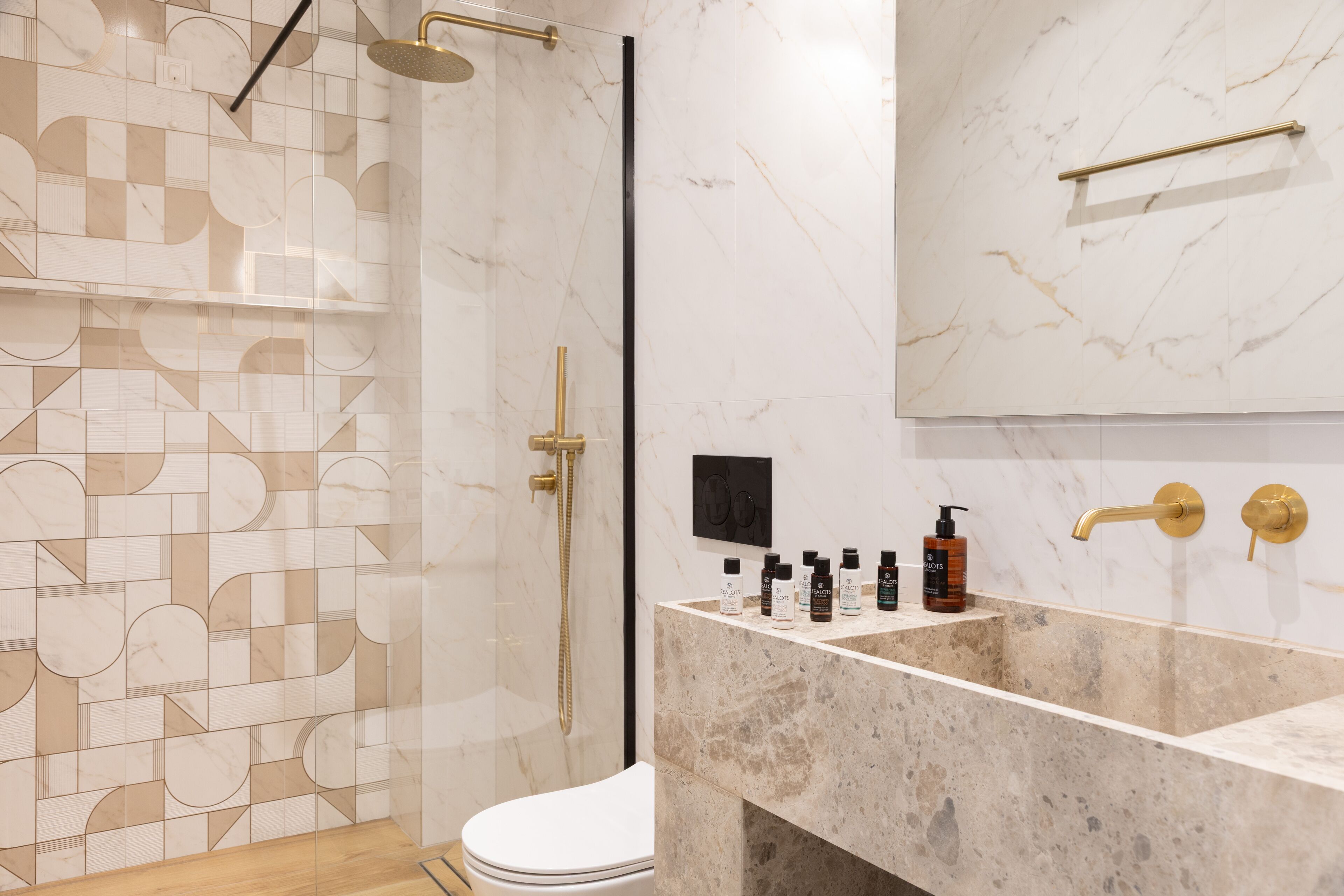 Une salle de bain moderne avec un carrelage aux motifs géométriques, une douche à parois de verre, un lavabo en marbre et des toilettes.