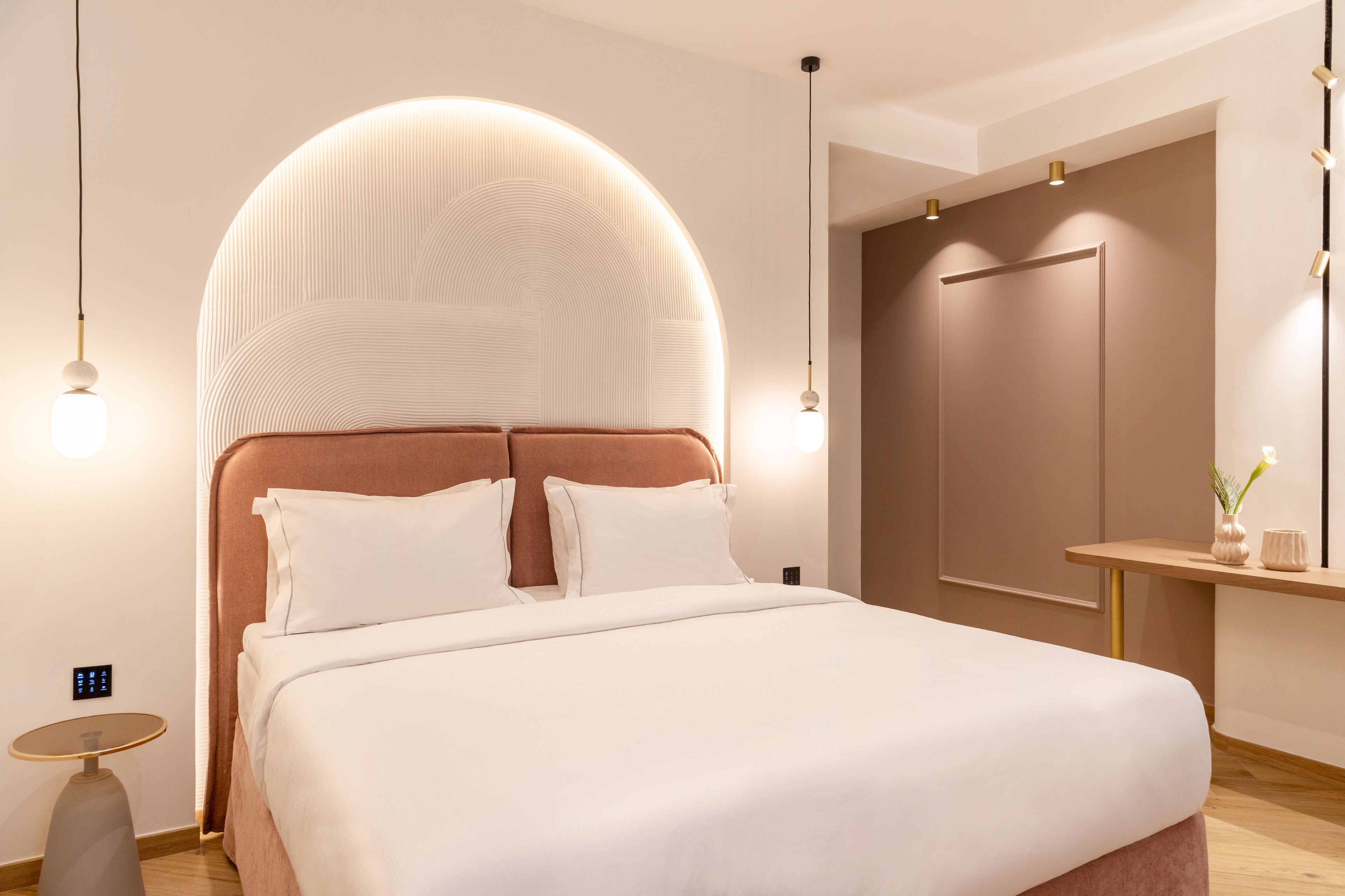 Un dormitorio moderno con una cama grande, cabecera redonda y una mesita de noche con lámpara.