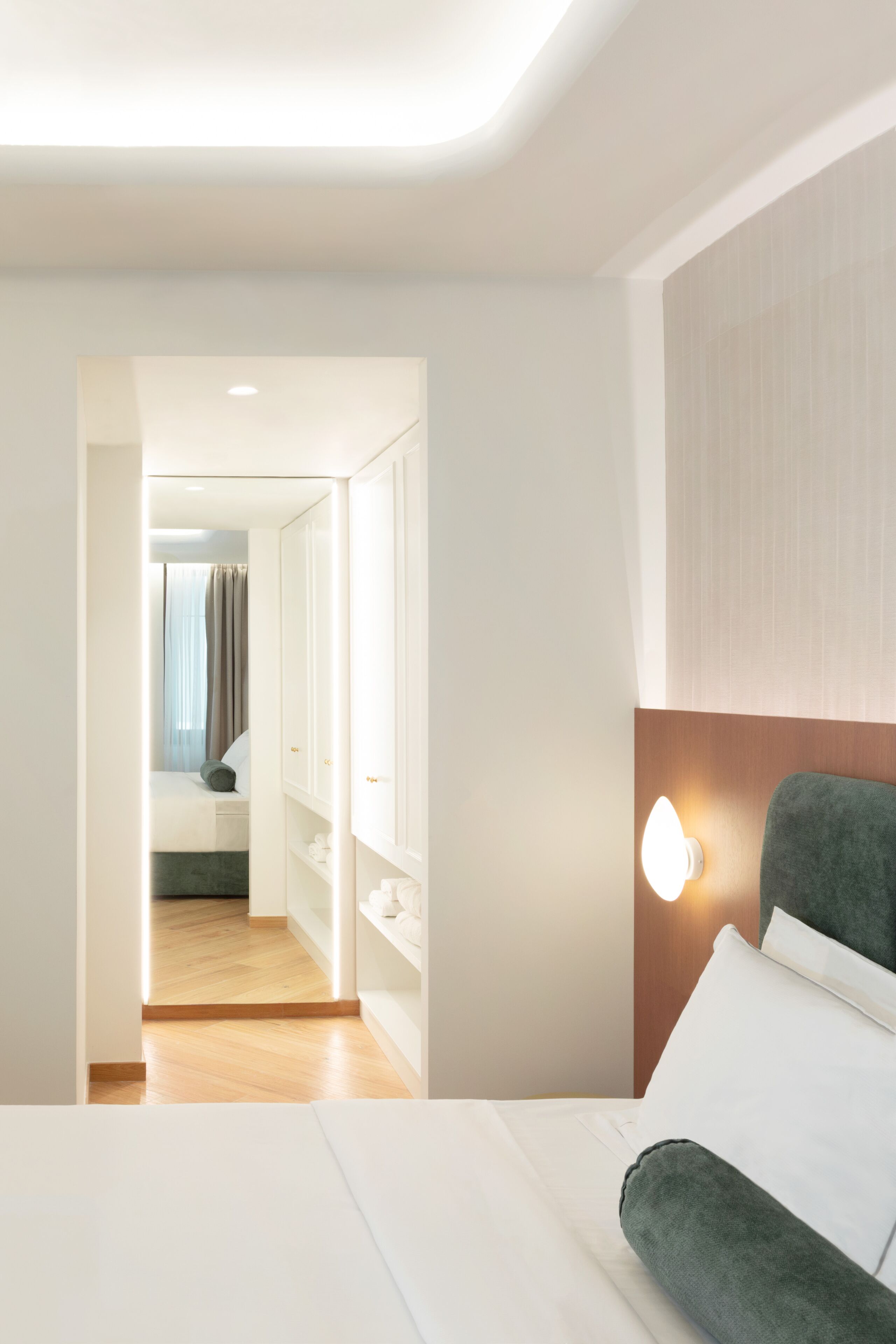 A hotel room with a bed, a nightstand, a wardrobe, and a mirror.