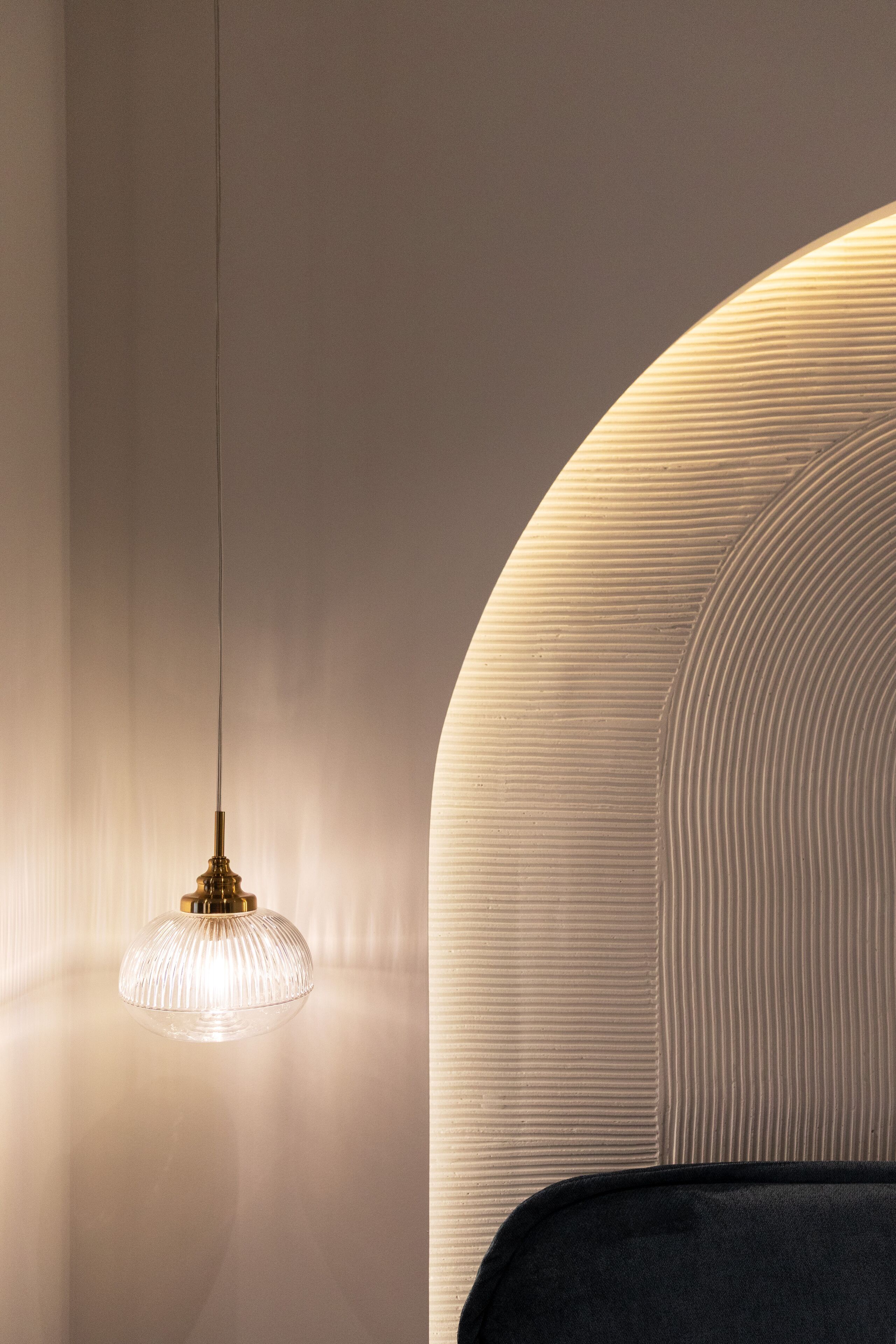Um interior moderno com uma parede curva singular e uma luminária pendente suspensa.