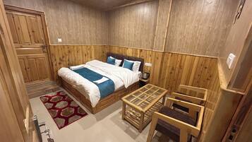 A wooden-paneled room with a bed, a small table, and a chair.