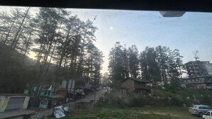 A view of a street lined with trees and buildings, including a mix of residential and commercial structures. - Hotel Ganpati (Lohaghat)