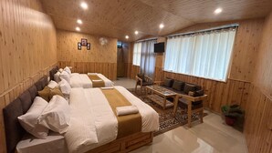 A wooden room with two beds, a sofa, a small table, and a TV. - Hotel Ganpati (Lohaghat)