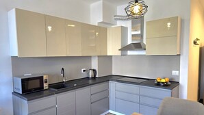 Een moderne keuken met grijze kastjes, een magnetron, een spoelbak en een waterkoker.