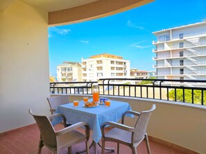 A balcony with a table, chairs, and a view of buildings. - Sunny Stay Apartment Durres 080 (Durres)