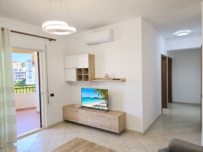 A modern living room with a flat-screen TV, wooden cabinet, and built-in shelving.