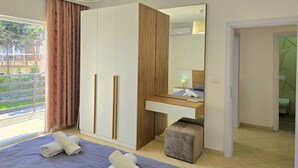 Et soveværelse med seng, garderobeskab, spejl, natbord og udsigt ud.
