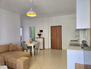 Un salon moderne comprenant un canapé, une table à manger et un coin cuisine avec une cuisinière.