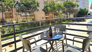 En balkon med et bord, stole, en vinflaske og glas.
