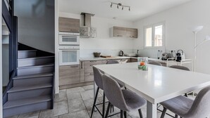 A modern kitchen with a central island, built-in ovens, and a dining area with bar stools.