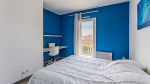 A bedroom with a bed, a desk, and a chair.