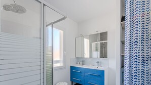 A modern bathroom with a shower, a large mirror, a sink with a vanity, and a patterned shower curtain.