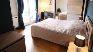 A bedroom with a bed, a desk, a chair, a wardrobe, and a lamp.