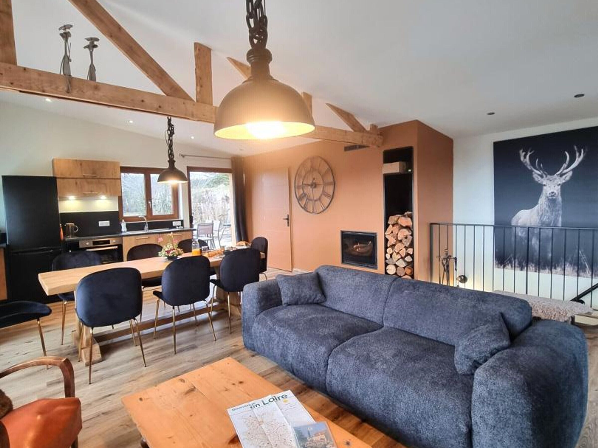 Een moderne woonkamer met een grijze bank, een houten eettafel en stoelen. Een houten salontafel met een tijdschrift staat op de voorgrond.
