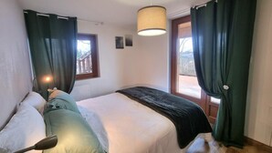 Une chambre à coucher avec un lit, une fenêtre, une porte et un luminaire suspendu.