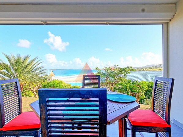 A dining area with a view of the beach and ocean.