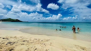 A beach with clear turquoise water, sandy shore, and a distant green hill. - Spacious sea-facing studio with air conditioning (Saint-Martin)