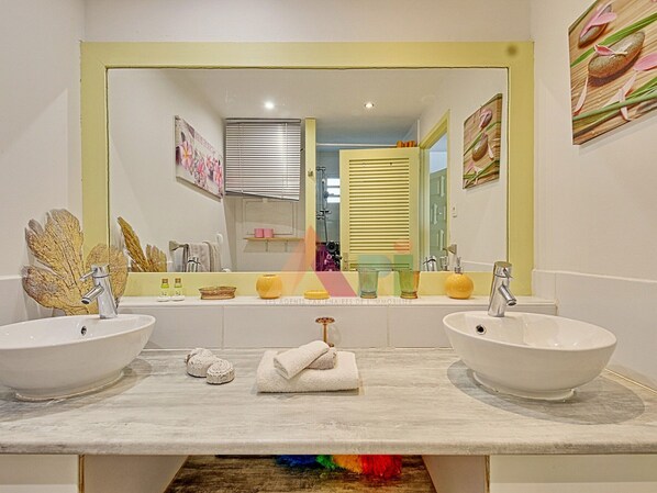 A bathroom with two white sinks, a large mirror, and a vanity with a towel rack. - Spacious sea-facing studio with air conditioning (Saint-Martin)