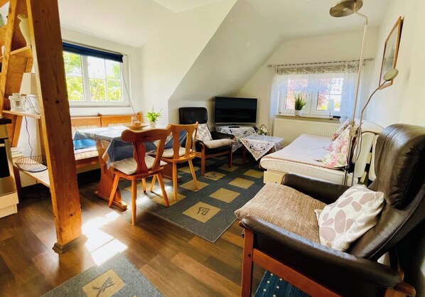 A cozy loft-style room with a dining area, a sofa, and a television.