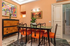 Un comedor con una mesa, sillas, un armario y obras de arte en las paredes.