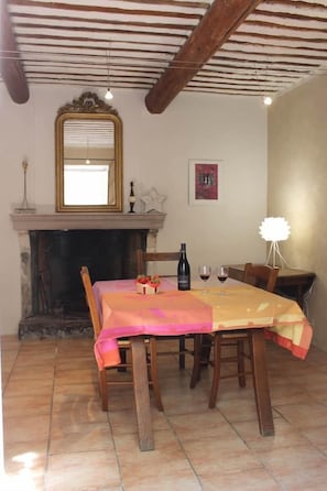 Un comedor con una mesa dispuesta para dos, una chimenea y un espejo sobre ella.