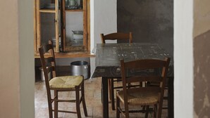 Een eetgedeelte met een tafel, stoelen, een raam met uitzicht en een muur met een poster.