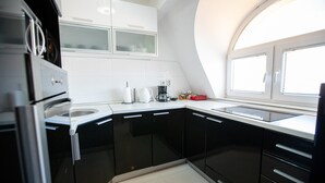 Una cucina moderna con mobili neri, piani di lavoro bianchi e forno integrato.