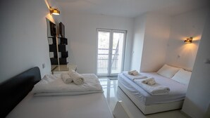Camera d'albergo con due letti, un'ampia finestra e uno specchio con televisore.