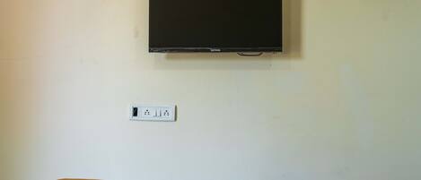 A wall-mounted television above a white electrical outlet.