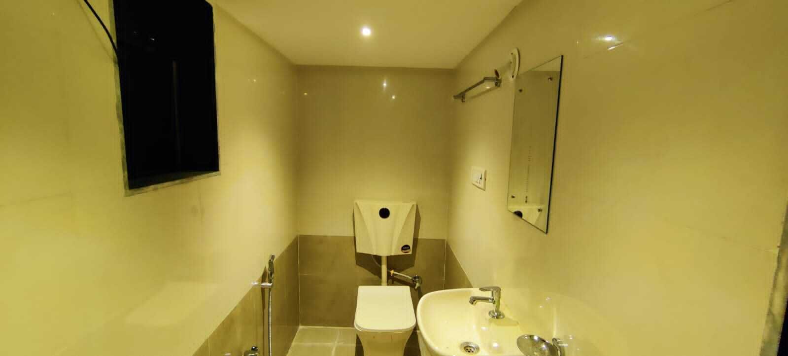 Une petite salle de bain bien éclairée, équipée de toilettes, d’un lavabo et d’un miroir.