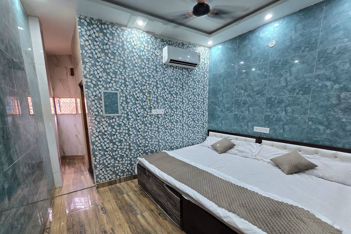 Ein modernes Schlafzimmer mit einem Bett, Holzboden, einer Wand mit Muster und einer Klimaanlage.