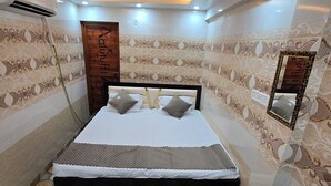 A bedroom with a bed, a ceiling fan, and patterned walls. - Shri Ganga Palace (Faizabad)
