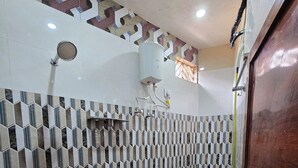 A bathroom with a tiled floor, a sink, a toilet, a shower, and a bucket. - Shri Ganga Palace (Faizabad)