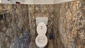 A bathroom with a toilet, a shower, and a sink. The walls are decorated with intricate patterns. - Shri Ganga Palace (Faizabad)