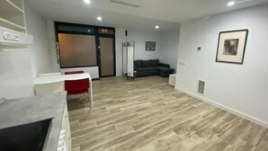 Ein modernes Wohnzimmer mit Holzboden, einem grauen Sofa, einem weißen Tisch und einem roten Sessel.