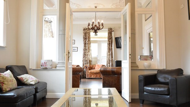 A spacious living room with a glass coffee table, leather sofas, and a chandelier. - Villa in Coo Near Waterfalls With Pool (Stavelot)