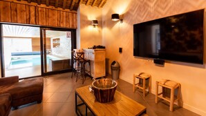 A modern living room with a wooden ceiling, a large TV, a wooden coffee table, and a view of an outdoor swimming pool. - Villa in Coo With Indoor Pool & Near Waterfalls (Stavelot)